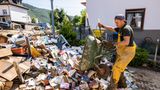Ahrbrück, Rheinland-Pfalz: Ein Helfer lädt vom Hochwasser beschädigte Bücher mit einer Schubkarre auf einem Haufen ab.