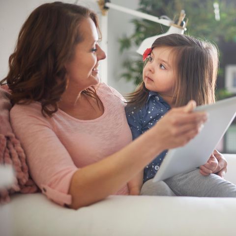 Kind schaut Mutter fragend an, während sie sich gemeinsam etwas auf einem Tablet anschauen