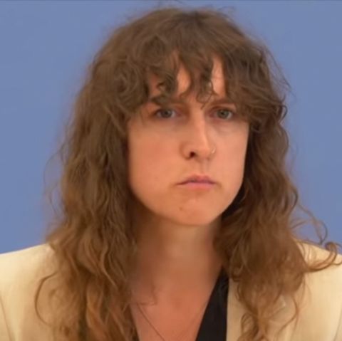 Eine weiße Frau mit halblangen, braunen Locken und ein weißer Mann mit schwarzer Brille und blondem Seitenscheitel sitzen