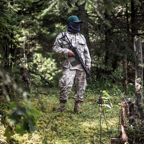 Im Tarnanzug mit Gesichtsmaske und bewaffnet mit einem Sturmgewehr patrouilliert ein Milizionär im Wald von Cherán