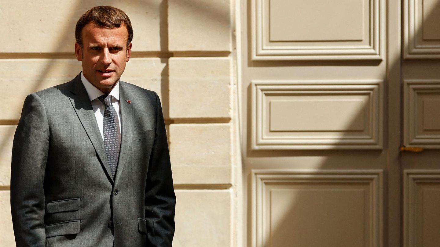 Emmanuel Macron steht vor einer massiven Holztür