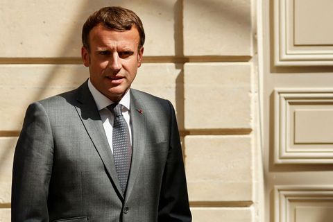 Emmanuel Macron steht vor einer massiven Holztür