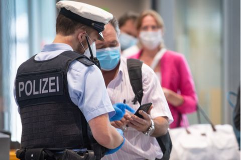 Einreisender zeigt einem Polizisten seinen digitalen Impfausweis