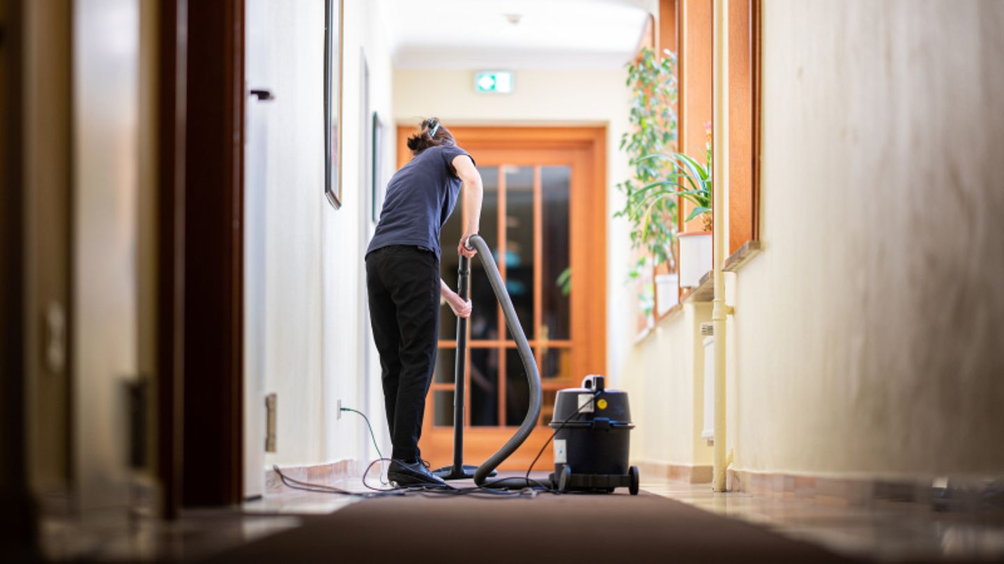 Eine Frau saugt in einem Hotel einen Flur.