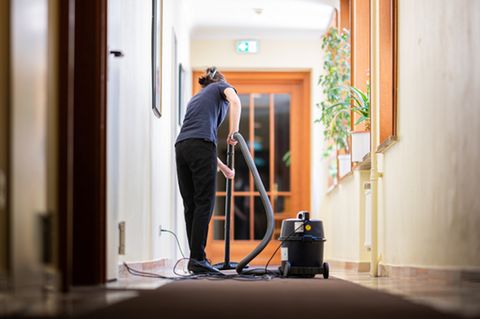 Eine Frau saugt in einem Hotel einen Flur.