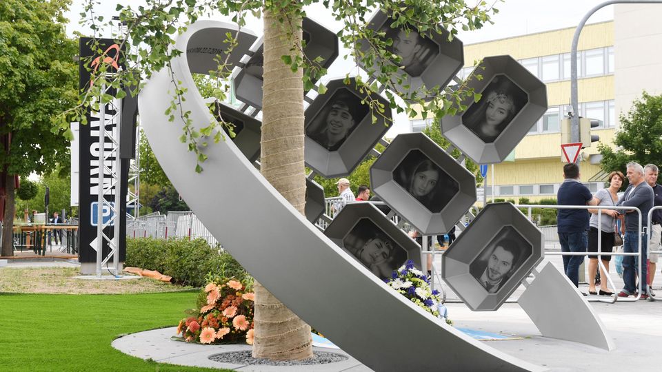 Das Mahnmal besteht aus einem Gingko-Baum, den ein zwei Meter hoher Edelstahlring, umfasst mit Fotos der Opfer