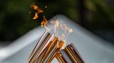 Zwei Fackeln reichen bei der Zeremonie im Hamacho Park in Nihonbashi nahe Tokio das olympische Feuer für bei einer Zeremonie weiter