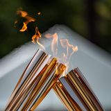 Zwei Fackeln reichen bei der Zeremonie im Hamacho Park in Nihonbashi nahe Tokio das olympische Feuer für bei einer Zeremonie weiter