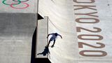 Ein Skateboarder fährt gerade von der linken Oberkante in eine Halfpipe mit großem "Tokyo 2020"-Schriftzug