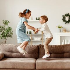 Mädchen und Junge springen auf Sofa