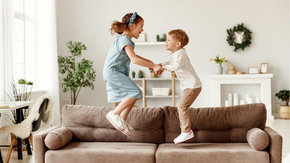 Mädchen und Junge springen auf Sofa