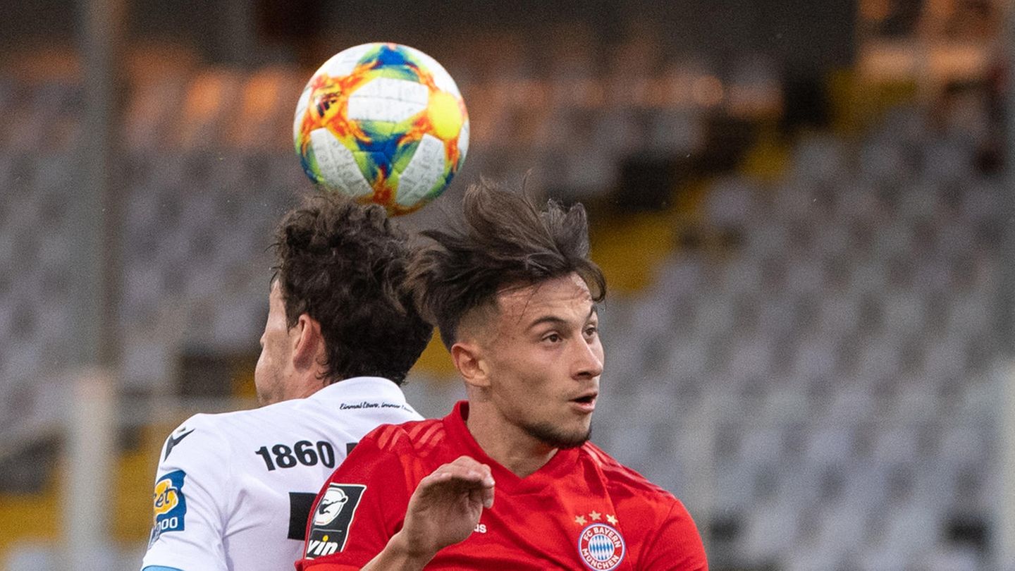 Zwei Fußballer - einer ganz in Rot, einer in Weiß und Dunkelblau – steigen Rücken an Rücken zum Kopfball hoch