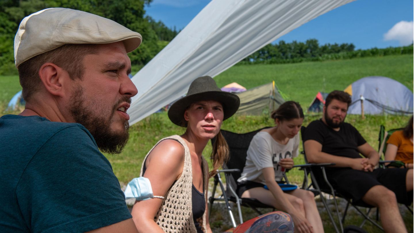 Stuhlkreis auf Klappstühlen: Die Veranstalter Nils (l) und Sandra (2.v.l) diskutieren in einer Gemeinschaftsrunde unter dem Sonnenschutz.