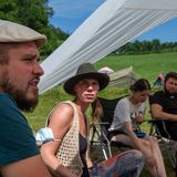 Stuhlkreis auf Klappstühlen: Die Veranstalter Nils (l) und Sandra (2.v.l) diskutieren in einer Gemeinschaftsrunde unter dem Sonnenschutz.