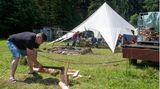 Erik hackt vor dem Gemeinschaftszelt Feuerholz für das Lagerfeuer am Abend