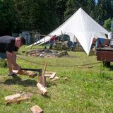 Erik hackt vor dem Gemeinschaftszelt Feuerholz für das Lagerfeuer am Abend