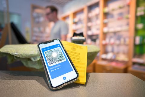 Ein Smartphone mit dem QR Code eines digitalen Impfausweises liegt auf dem Tisch einer Apotheke