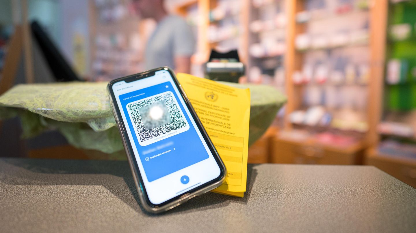 Ein Smartphone mit dem QR Code eines digitalen Impfausweises liegt auf dem Tisch einer Apotheke