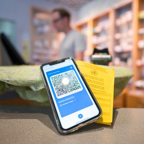 Ein Smartphone mit dem QR Code eines digitalen Impfausweises liegt auf dem Tisch einer Apotheke