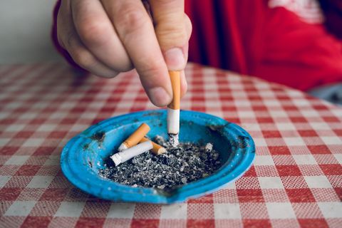 Eine Hand drückt eine Zigarette in einem Aschenbecher aus
