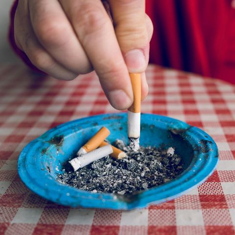 Eine Hand drückt eine Zigarette in einem Aschenbecher aus