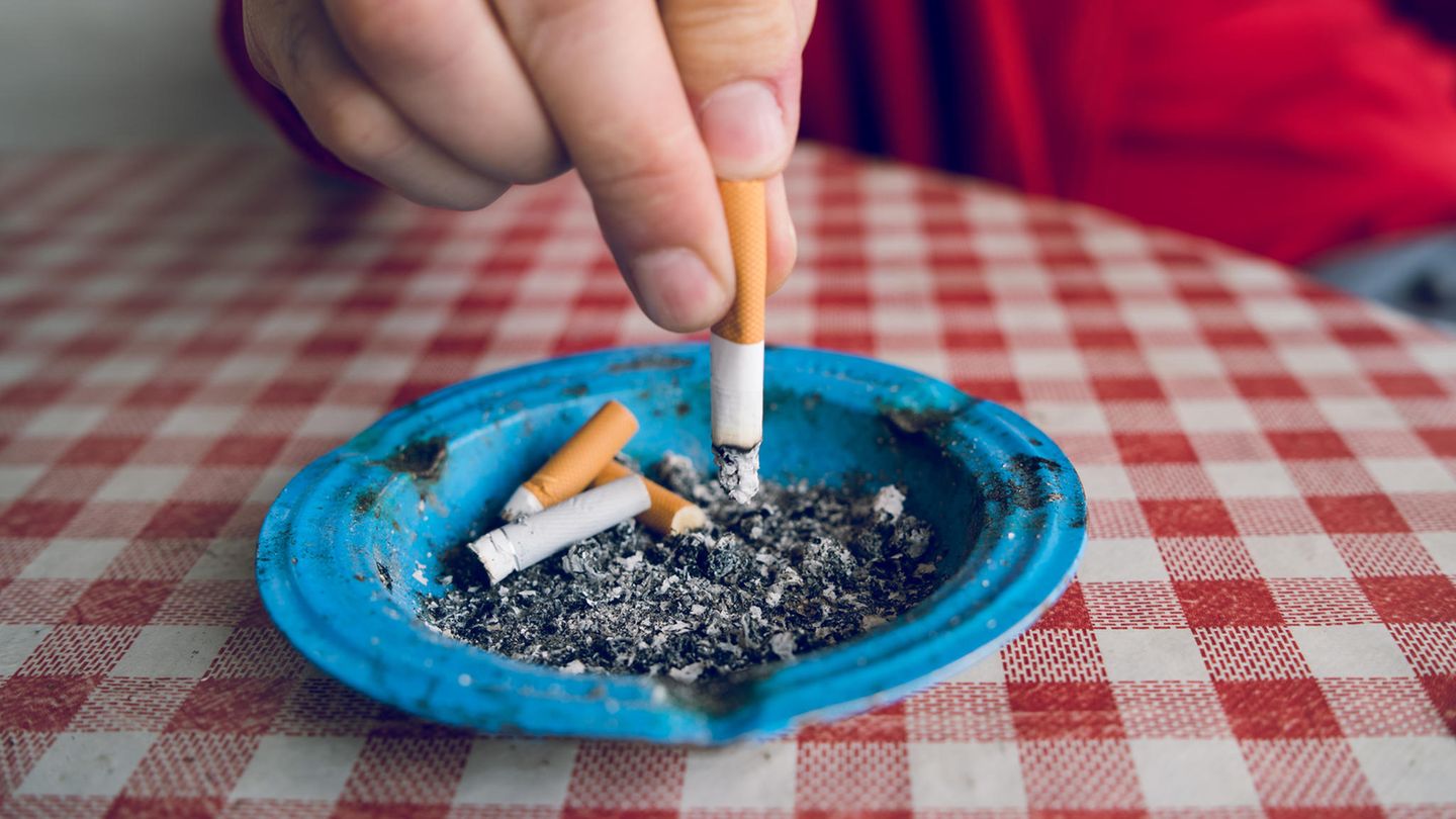 Eine Hand drückt eine Zigarette in einem Aschenbecher aus