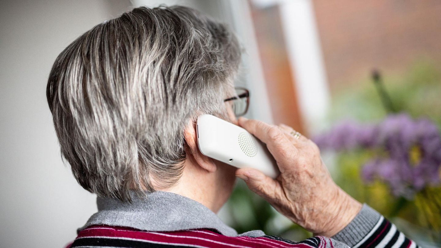 Seniorin telefoniert und schaut dabei aus dem Fenster.