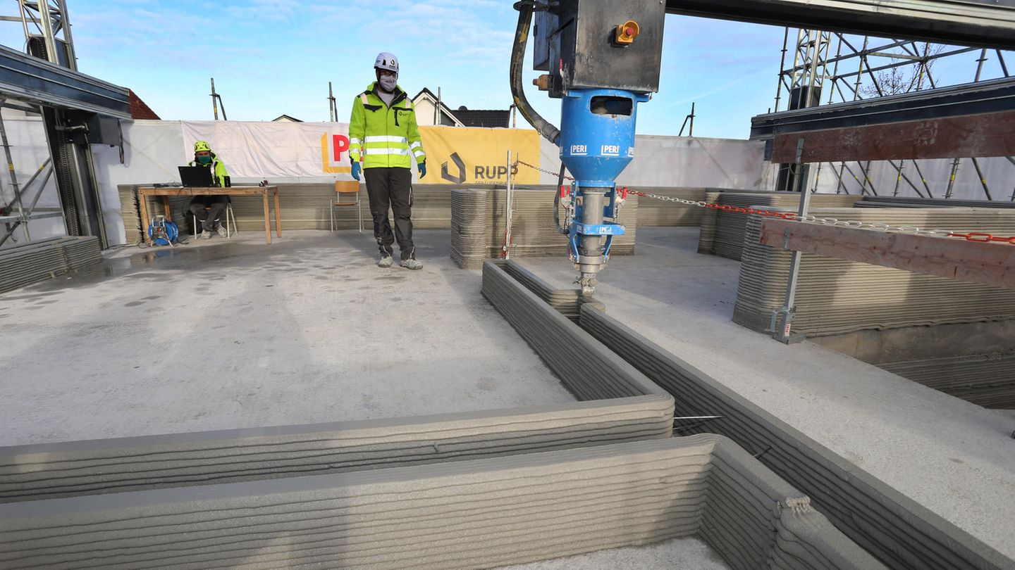Haus wird gedruckt Wände werden im ersten Stock eines Rohbaus mittels eines 3D-Betondruckers in Schichten hoch gezogen.