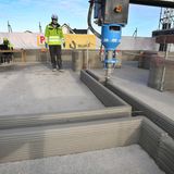 Wände werden im ersten Stock eines Rohbaus mittels eines 3D-Betondruckers in Schichten hoch gezogen.