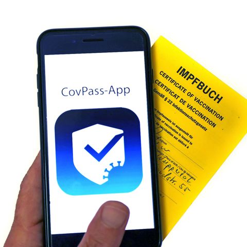 Ein Impfbuch und ein Smartphone mit der CovPass-App