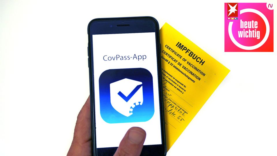 Ein Impfbuch und ein Smartphone mit der CovPass-App