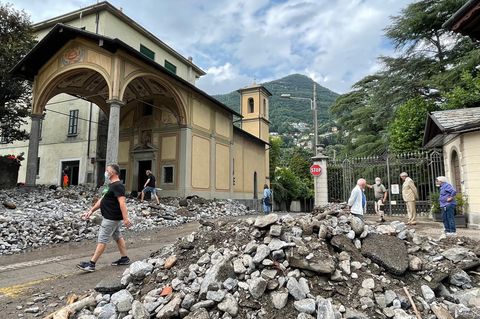 Passanten stehen neben dem Schutt, den ein Unwetter bis in die Stadt gespült hat.