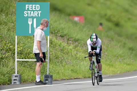 Ein Mann steht am Streckenrand, während ein Rennradfahrer in Montur an ihm vorbeifährt