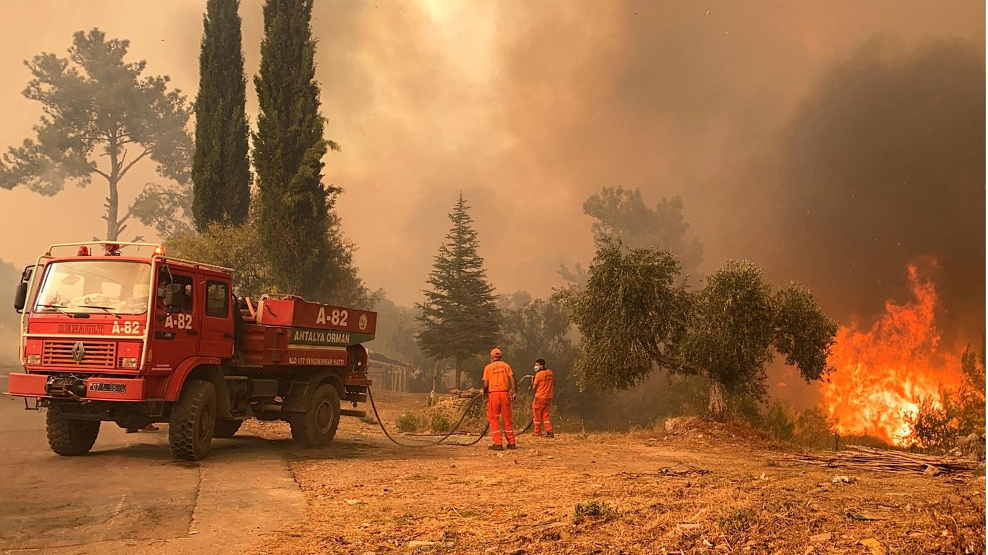 Ein Löschfahrzeug und zwei Feuerwehrleute in einer brennenden Landschaft