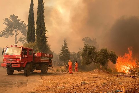 Ein Löschfahrzeug und zwei Feuerwehrleute in einer brennenden Landschaft
