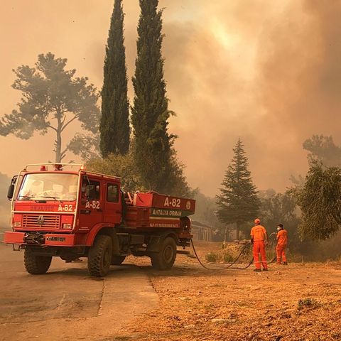 Ein Löschfahrzeug und zwei Feuerwehrleute in einer brennenden Landschaft