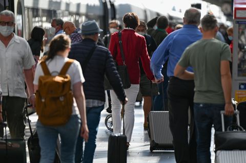 Viele Reisende laufen durch einen Bahnhof
