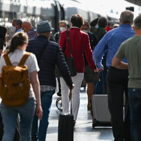 Viele Reisende laufen durch einen Bahnhof