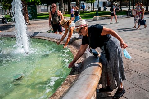Touristen erfrischen sich bei Temperaturen über 40 Grad mit Wasser aus einem Brunnen auf dem Syntagma-Platz in Athen