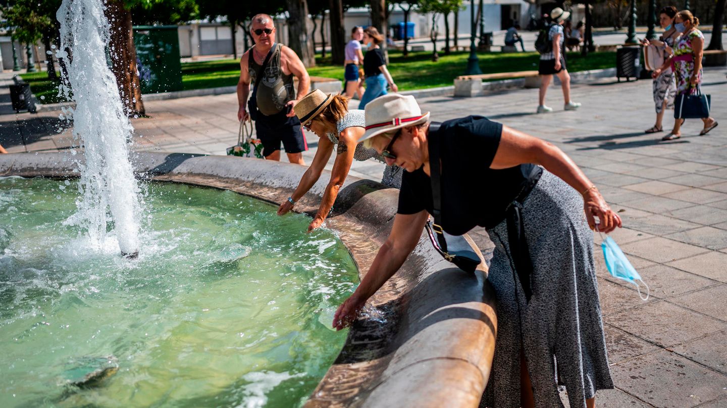 Touristen erfrischen sich bei Temperaturen über 40 Grad mit Wasser aus einem Brunnen auf dem Syntagma-Platz in Athen