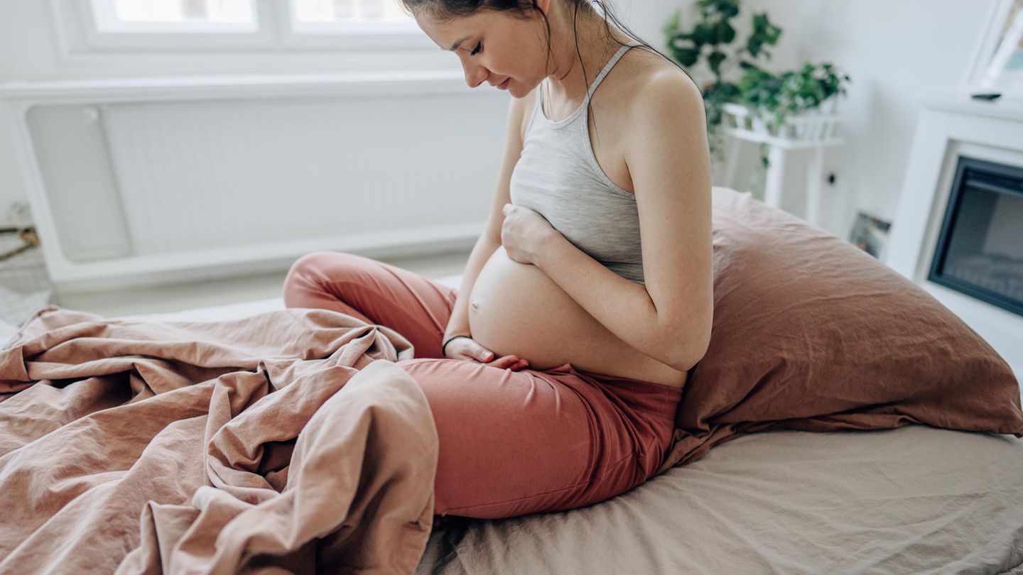 Coronavirus Schwangerschaft Impfung: Eine schwangere Frau sitzt in einem Bett