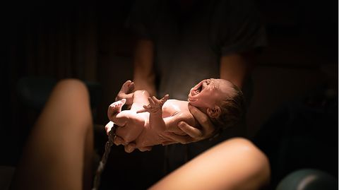 Ein Baby mit Nabelschnur in den Händen eines Vaters