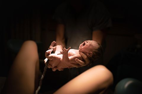 Ein Baby mit Nabelschnur in den Händen eines Vaters
