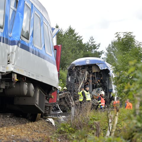 Rettungskräfte in gelben und orangen Warnwesten stehen zwischen einem gestauchten und einem am Ende offenen Zugwaggon