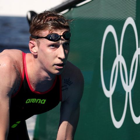 Florian Wellbrock steigt aus dem Wasser neben den Olympischen Ringen weiß auf grün