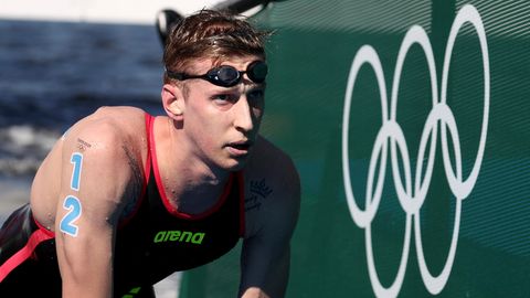 Florian Wellbrock steigt aus dem Wasser neben den Olympischen Ringen weiß auf grün