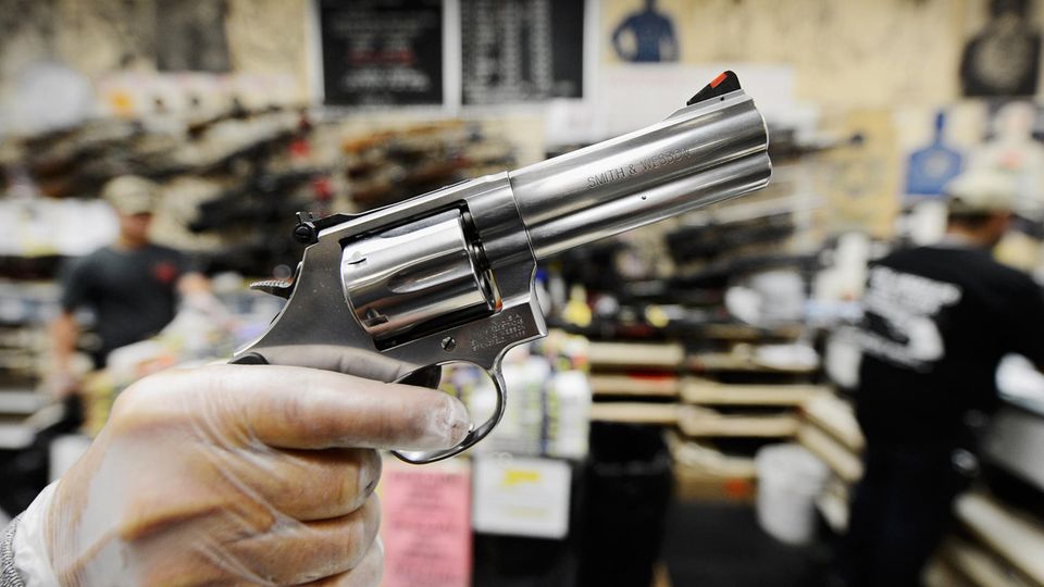 Smith & Wesson Eine rechte, weiße Männerhand in einem durchsichtigen Gummihandschuh hält einen silbernen Revolver mit kurzem Lauf