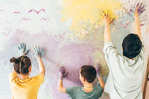 Mutter und zwei Kinder bemalen eine Wand mit den Händen