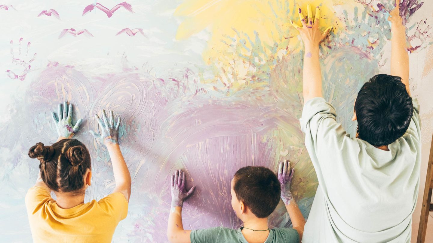 Mutter und zwei Kinder bemalen eine Wand mit den Händen