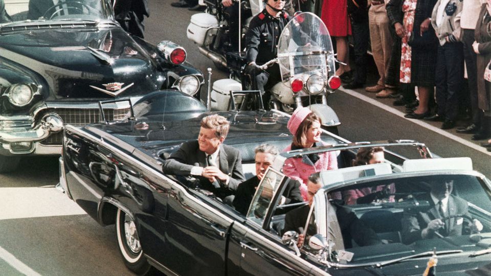John F. Kennedy (l.) und Ehefrau Jackie bei der verhängnisvollen Fahrt durch Dallas im Jahr 1963